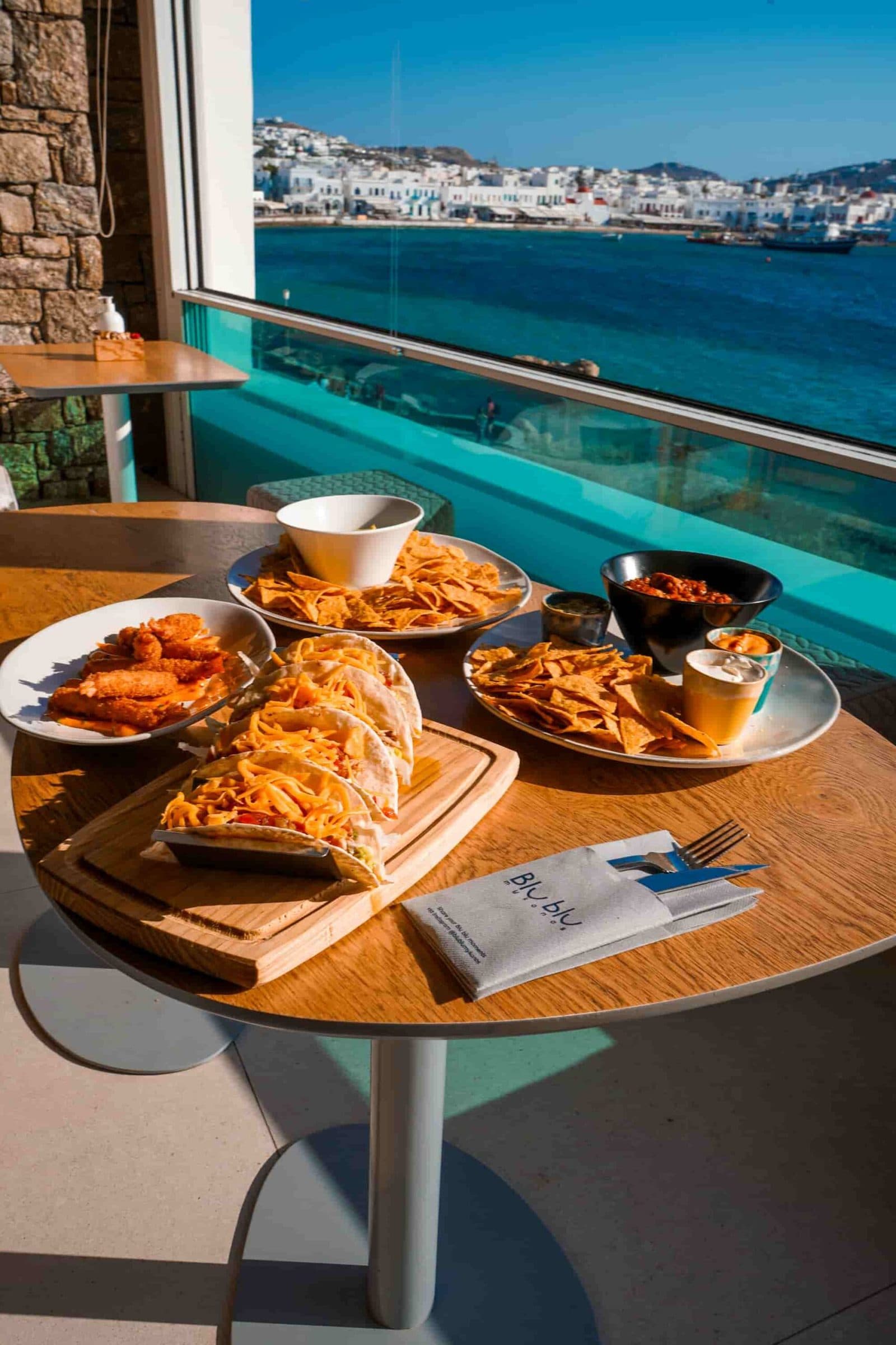 Πιάτα brunch σε τραπέζι πάνω από τη θάλασσα, με φόντο τη Χώρα