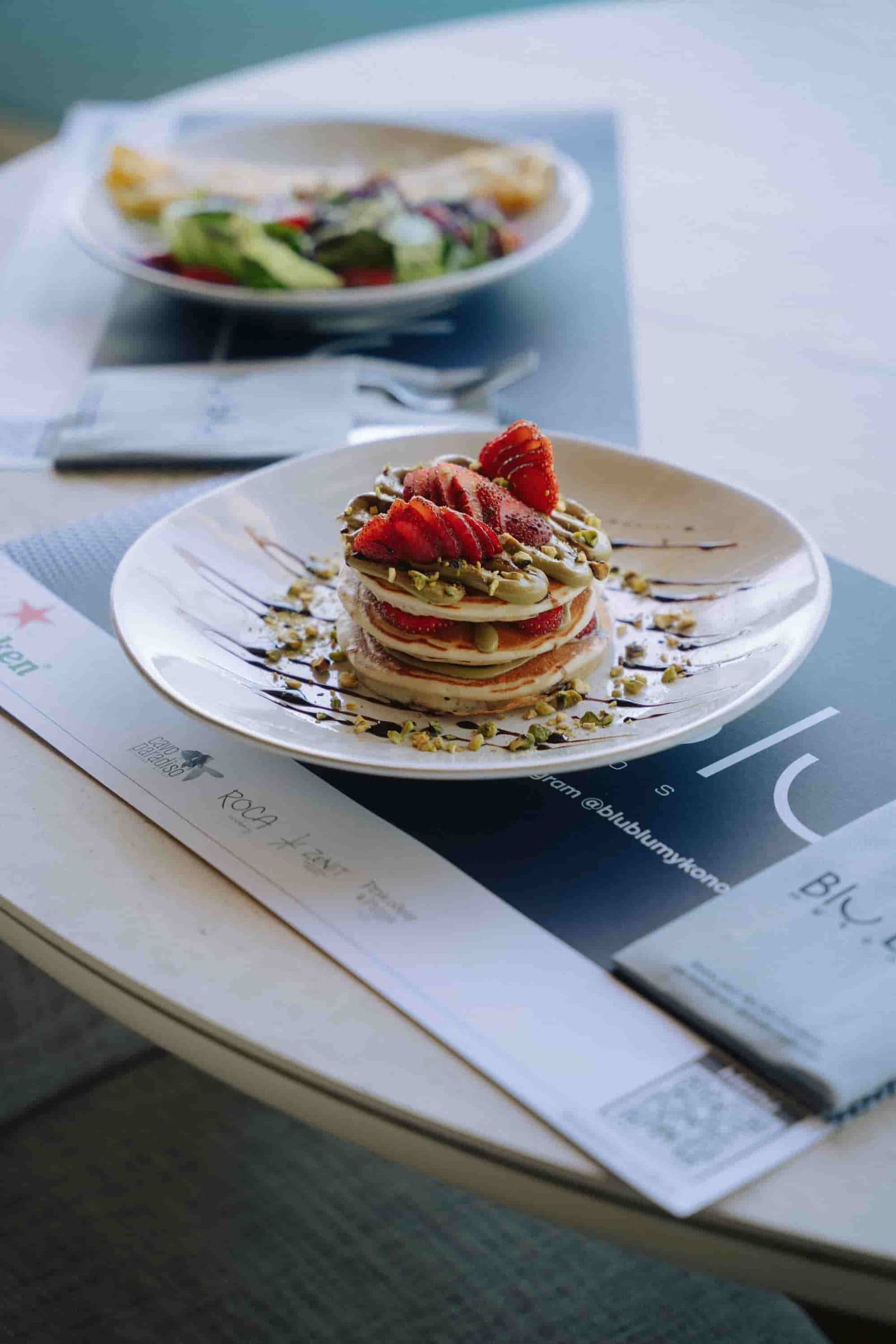 Pancakes φιστικιού με φράουλες σε τραπέζι δίπλα στη θάλασσα